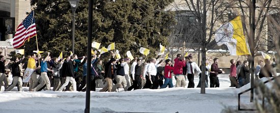 A group of Catholics storms the Lower Quad at the University of St. Thomas March 13, cheering and waving Vatican City flags and an American flag. Rosie Murphy/TommieMedia