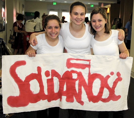 After the girls performed in finals, (from left to right) Maggie Schmidt, Carly Zimmerman and Kateri Schmidt hold a sign from their performance that reads solidarity in Polish. Photo courtesy of Greg Schmidt
