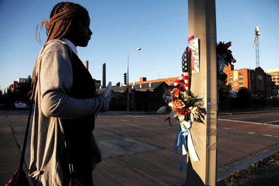 MOURNING THE VICTIMS: A woman pauses in front of a pole decorated with flowers, flags and a child’s drawing Sept. 18 outside the Navy Yard in Washington, two days after a gunman went on a shooting spree. Authorities said 13 people were killed, including the gunman, and at least eight were injured at the facility, which is the Naval Sea Systems Command headquarters. CNS photo / Jonathan Ernst, Reuters