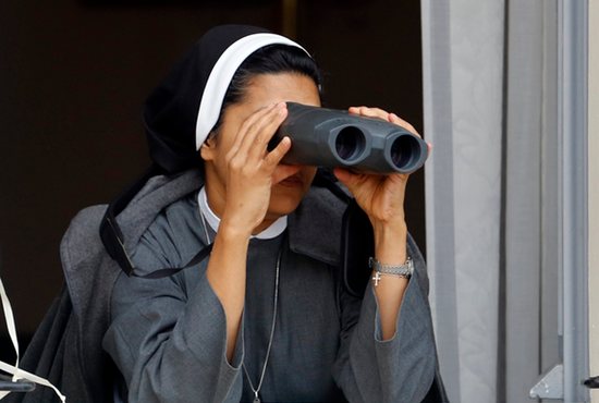 POPE WATCHING: A nun looks through binoculars as Pope Francis arrives to celebrate Mass outside the Basilica of St. Francis in Assisi, Italy, Oct. 4. CNS photo/Stefano Rellandini, Reuters