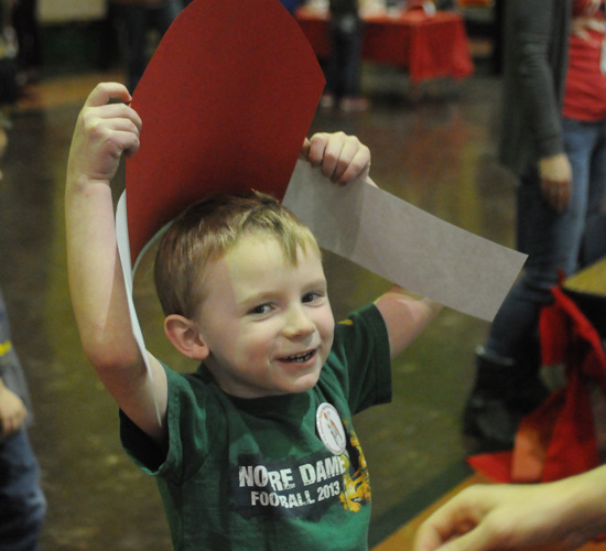 Preschooler Ronan Murphy waited to have the paper miter he made stapled together so he could wear it.