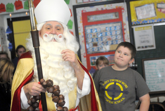 Jesuit Father Joseph Weiss, pastor of St. Thomas More parish in St. Paul, dressed as St. Nicholas Dec. 6 for a special day of activities for preschoolers and a visit to k-8 students at the parish school. Above, third-grader Declan Hegarty admires the costume.