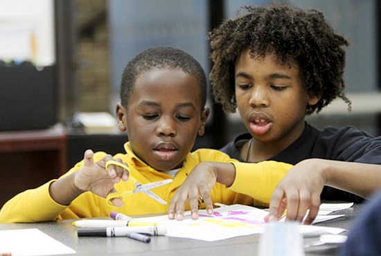 Elijah Short, right, a sixth-grader at St. Stephen School in Anoka, helps his kindergarten buddy Ajim Tubuo work on an art project for religion class as part of the school’s Disciples and Friends program. Dave Hrbacek/ The Catholic Spirit