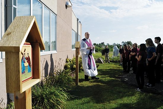 Father Nate Meyers blesses the new Stations of the Cross at St. Francis Xavier school in Buffalo. Bob Zyskowski/The Catholic Spirit
