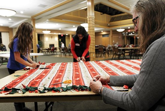 Karen Anthony, right, of St. Joseph in Miesville works on a blanket Dec. 1 at an event put on by a group called Women Inspiring Women at St. Elizabeth Ann Seton in Hastings. Women from SEAS and neighboring parishes made a total of 16 blankets, which will be given to the needy. Parishioner Jeanne Loesch collects these blankets and others for distribution through a program she started called Covered By His Love. Also working on the blanket are Amy Gapp, left, and her mother, Christina. Dave Hrbacek/The Catholic Spirit