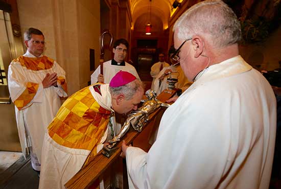 Archbishop Bernard Hebda kisses a crucifix held by Father John Bauer, pastor of the Basilica of St. Mary in Minneapolis, at the start of the Rite of Reception May 12 at the Basilica. Archbishop Hebda knocked on the outside door to start the event, then was presented with the crucifix upon entering.