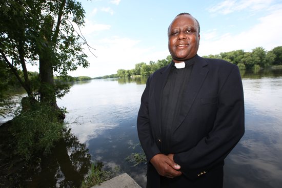 Father Robert Mutui of the Diocese of Kitui, Kenya, enjoys seeing Minnesota’s copious amounts of water, including the Mississippi River, which runs less than a mile from St. John the Baptist in Dayton. He said he wishes he could use “a giant pipe” to take some of the water from the river back to his country, which often experiences severe drought. Dave Hrbacek/ The Catholic Spirit