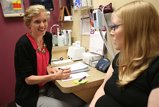 Sarah Slattery, left, physician assistant at AALFA Family Clinic in White Bear Lake, talks with patient Becca Kempenich, who was there with her husband, Dan, and newborn son, Xander. Dave Hrbacek/The Catholic Spirit