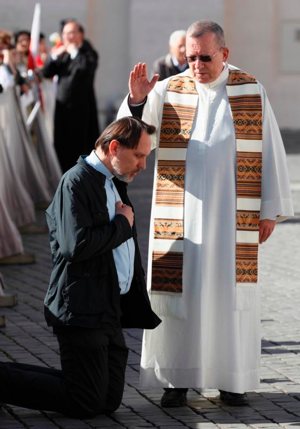 A priest hears a confession in St. Peter's Square at the Vatican, April 28, 2014. God's mercy is highlighted in the sacrament of reconciliation, Pope Francis said in a message to bishops, priests and church workers attending Italy's annual week of liturgical studies. CNS photo/Paul Haring
