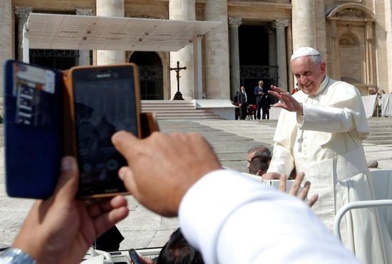 A pilgrim takes a cell phone picture as Pope Francis waves at the end of his weekly audience Sept. 28 in St. Peter's Square at the Vatican. CNS photo/Remo Casilli, Reuters