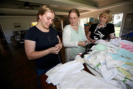 Christelle Hagen, center, works on baby clothing with her daughter, Emilie-Rose, left, and mother Marilyn Kallio. Dave Hrbacek/The Catholic Spirit 