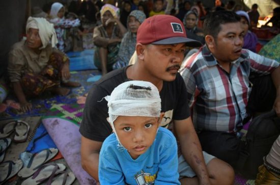 A young earthquake survivor sits with his family inside a makeshift tent July 30 on the island of Lombok in Indonesia.