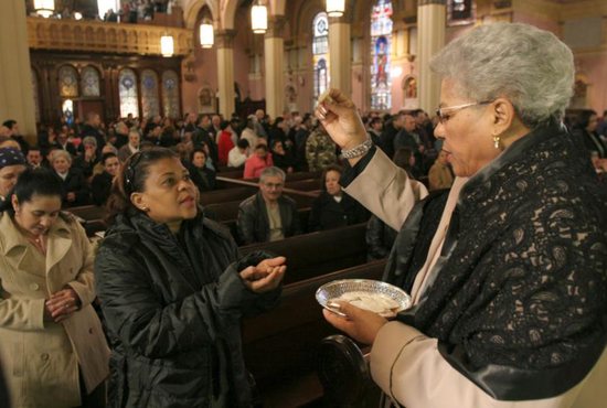 An extraordinary minister of the holy Eucharist distributes Communion during Mass at Transfiguration Church in the Williamsburg section of Brooklyn, N.Y.