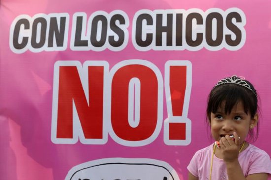 A child stands next to a sign reading "With the Children, No!" during a protest in early February against child abuse and violence in Lima, Peru.