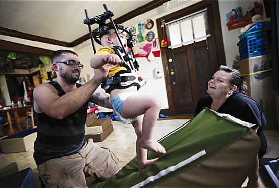 Kayden Peltier does some exploring in the living room with help from his parents, Kyle and Nicolle