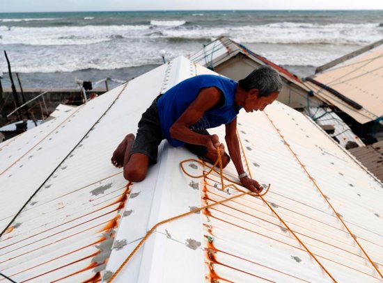 A man secures the roof of his home Sept. 14 in preparation for super Typhoon Mangkhut in the village of Aparri, Philippines.