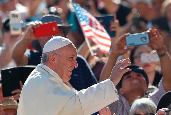 The U.S. flag is seen as Pope Francis greets the crowd during his general audience in St. Peter's Square at the Vatican Sept.