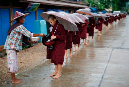 A woman offers food alms to Buddhist novices at Hpa-An town, Myanmar, Aug. 2. The U.S. International Commission on Religious Freedom singled out 28 countries for their repression of religious liberty in its annual report, issued Aug. 29.