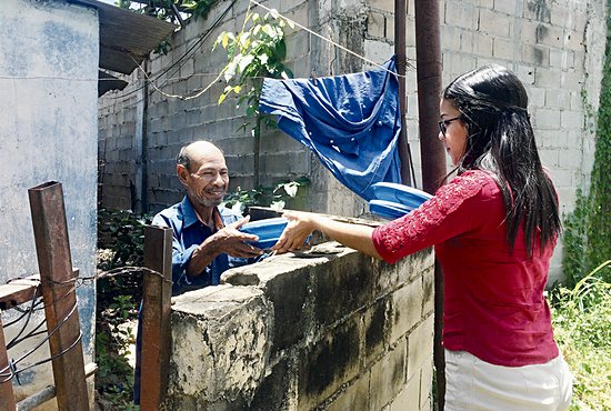 Dubraska Medina, a parishioner of Jesucristo Resucitado, delivers food to a man in need in San Félix, Venezuela.