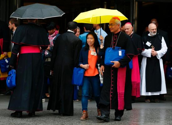 Indonesian youth delegate Anastasia Indrawan share an umbrella with an unidentified bishop as they leave a session of the Synod of Bishops on young people, the faith and vocational discernment at the Vatican