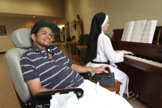 In this April 19, 2011, file photo, patient Warren Saunders smiles as Dominican Sister Agnes Mary plays the piano at Rosary Hill Home in Hawthorne, N.Y., where the nursing home staff provides palliative care to people with incurable cancer. Catholic experts have called for palliative care to become standard around the world.