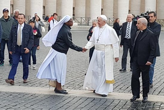 Pope Francis greets a woman religious as he makes a surprise visit to a free health clinic for the needy in St. Peter's Square at the Vatican Nov. 16. The clinic was open for a week in advance of the Nov. 18 observance of World Day for the Poor. 