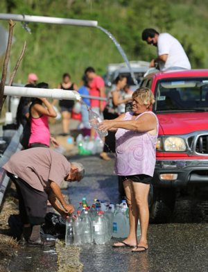 People fill containers with spring water from a mountain in Utuato, Puerto Rico, after Hurricane Maria devastated the island in 2017.
