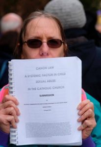 A protester holds a document Nov. 12 outside the hotel where bishops gather for a day of prayer and reflection in Baltimore.