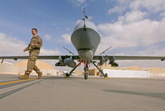 A U.S. service member passes in front of an MQ-9 Reaper drone to help to step up the fight against the Taliban at the Kandahar air base in Afghanistan. 