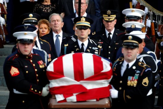 Former U.S. President George W. Bush follows a military honor guard as they carry the flag-draped casket of former President George H.W. Bush after his father's state funeral Dec. 5 at the Episcopal Church's Washington National Cathedral