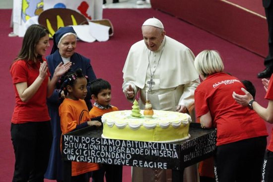 Pope Francis is presented with a cake on the eve of his 82nd birthday during a Dec. 16 audience with children and families from the Santa Marta Dispensary, a Vatican charity that offers special help to mothers and children in need.
