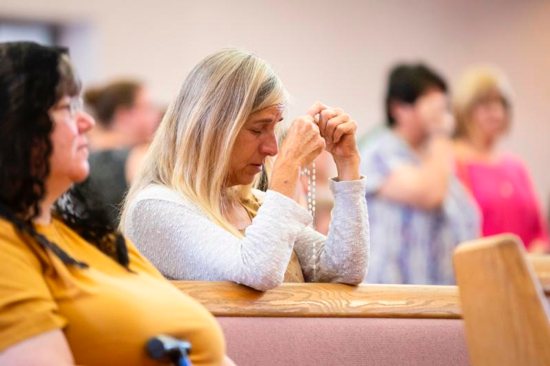 A worshipper prays with a rosary near a reliquary containing St. John Vianney's incorrupt heart at St. Anne Church in Gilbert, Ariz., May 6, 2019.