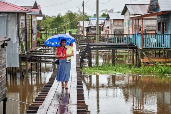 Carrying a child, a woman walks along a raised sidewalk