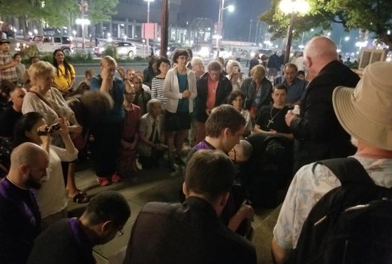Archbishop Terrence Prendergast of Ottawa, Ontario, right, holds a bottle of holy water while blessing a crowd of people during a prayer vigil outside The Koven nightclub in Ottawa