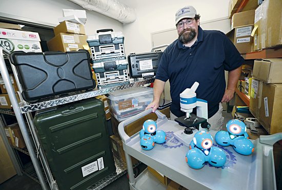 Michael Gerard, manager of the Lending Library at the University of St. Thomas, shows examples of what Catholic schools can borrow for their classrooms: dash robots and a microscope.
