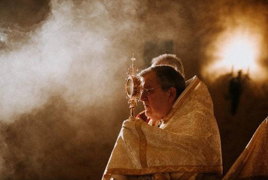 Cardinal Raymond Burke holds the monstrance during Mass