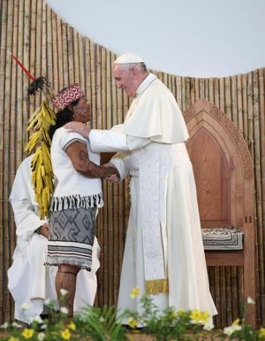 Pope Francis is greeted by a member of an indigenous group from the Amazon region