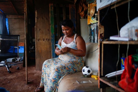 Tatiana Araujo de Sirqueira, 33, uses a cell phone in her home set up on land near Planalto Palace during the coronavirus pandemic in Brasília, Brazil, March 3, 2021. In a message to participants of the World Bank Group and International Monetary Fund 2021 virtual spring meetings, Pope Francis said poor countries cannot be expected to recover from the current financial crisis if the world returns to an economic model in which a small minority of people owns half of the world's wealth.