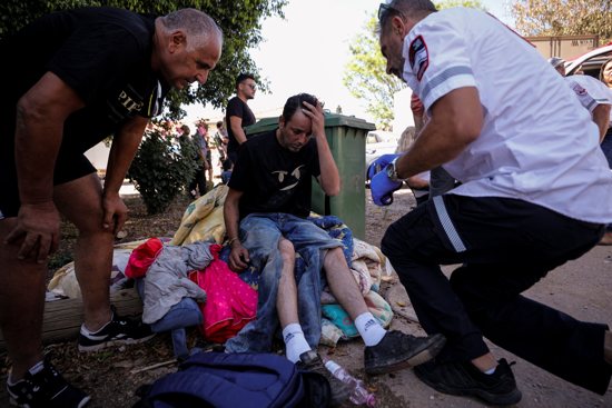 An Israeli medic treats a man who was wounded after a rocket launched from the Gaza Strip landed near homes in Moshav Zohar, Israel, May 13, 2021.