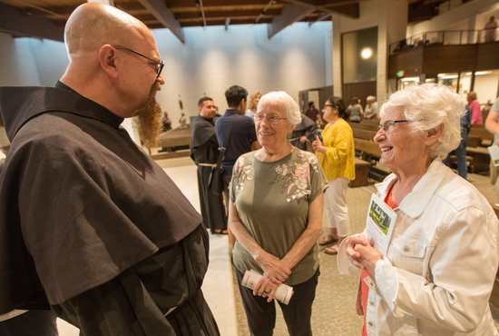 Father Matthew Malek, a Conventual Franciscan Friar at St. Bonaventure in Bloomington, talks with parishioners Agrita Majeres