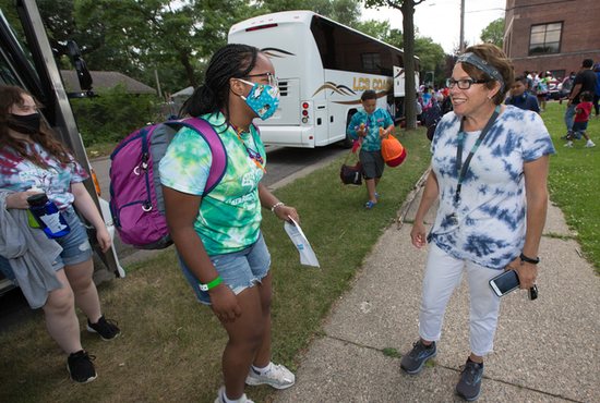 C.J. McGowan, right, of City Connects, greets Saisha Torrence, who recently graduated from the eighth grade at Ascension Catholic School, and others July 9 upon their return from a week at Catholic Youth Camp near McGregor.