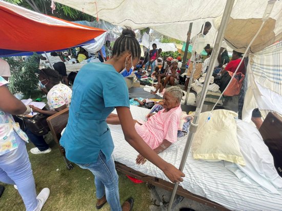 A woman is assisted by a member of the medical personnel outside a hospital in Les Cayes, Haiti, Aug. 16, 2021, following a magnitude 7.2 earthquake two days earlier.