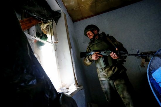 A militant of the self-proclaimed Luhansk People's Republic stands inside an abandoned house near fighting on the line of separation from the Ukrainian armed forces in Luhansk, Ukraine, July 16, 2021. A bishop in eastern Ukraine accused the Russian-backed separatists of barring Latin-rite Catholic clergy from their territory and urged Western church leaders to speak out amid new fears of violence.