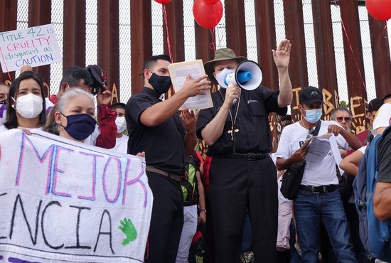 Bishop Edward J. Weisenburger of Tucson, Ariz., center, leads a prayer using a megaphone during the "Restore Protections for Holy Families: Prophetic Action to #SaveAsylum" demonstration in Nogales, Mexico, Sept. 25, 2021.