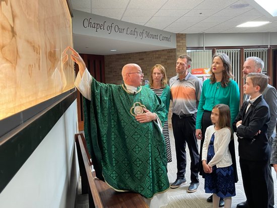 Father Brian Lynch, associate pastor of Transfiguration in Oakdale, explains details in an approximate half-size replica of the shroud of Turin that is displayed in the church’s Elijah Gallery, located between the main church and the chapel. With Father Lynch, clockwise, are Transfiguration parishioner Mary Byrne, Pete Quimby, and the Oakes family, parishioners of St. Michael in Stillwater: Renee and Matthew with children Evelyn and Henry.