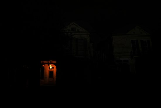 A front porch in New Orleans is lit by a flame on a dark street Aug. 31, 2021, as the city remains without power in the aftermath of Hurricane Ida.