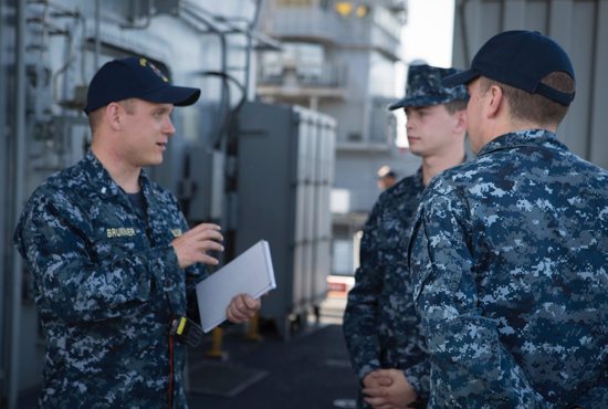 In this 2016 file photo, Father William J. Brunner, a Navy chaplain and a priest of the Diocese of Green Bay, Wis., interacts with two sailors while he makes his routine maintenance checks aboard the Navy warship USS America docked in San Diego.
