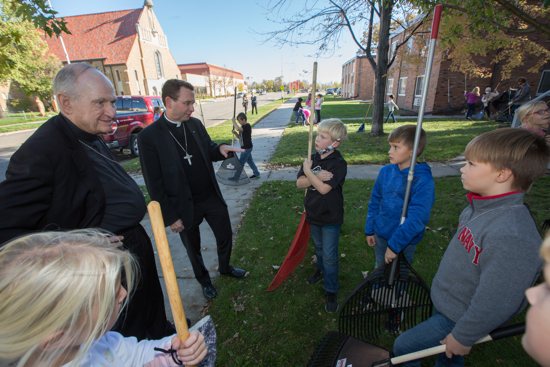 Bishop Pates, left, and Bishop-designate Cozzens, center, visit with third-graders of Sacred Heart School in East Grand Forks. The students were raking leaves at a home across the street from their school and its parish Oct. 18 for the school’s annual Rake-a-Thon service day and fundraiser.
