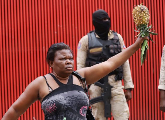 A woman in Port-au-Prince, Haiti, offers pineapple for sale next to a riot police officer Oct. 18, 2021, as Haitians mount a nationwide strike to protest a growing wave of kidnappings.