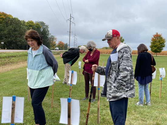 Retreatants Ann and Chris Biehn, neighbors of Father Kevin Clinton, participate in a “creation story walk” in front of Immaculate Conception church, where participants walked in silence past 57 stations with photos and timeframes about the unfolding of creation on earth.
